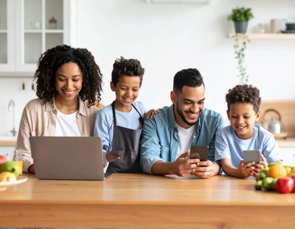 Family in kitchen on devices