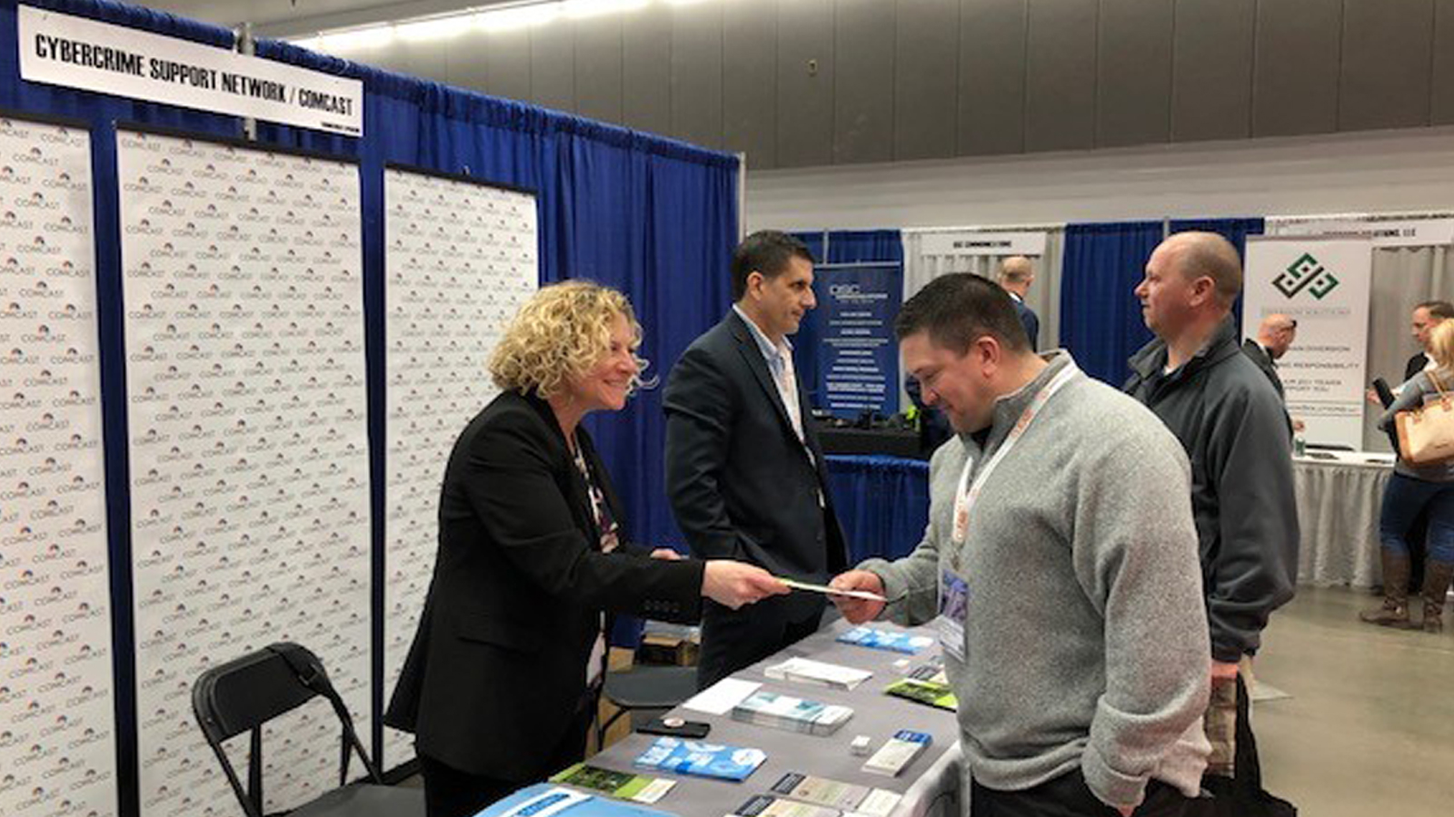 Volunteers distribute pamphlets at the Comcast and Cybercrime Support Network booth.