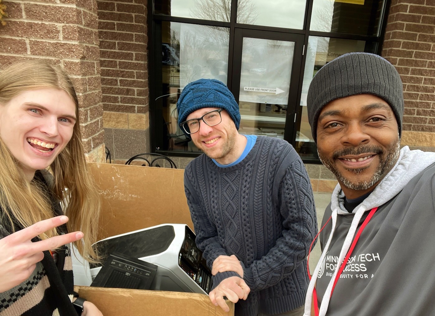 MN Tech for Success team posing in front of store with a box of donated technology.