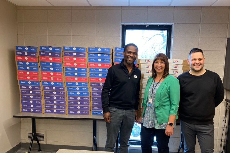 Arrive Ministries staff smiles in front of 100 laptops donated by Comcast.